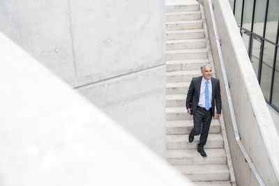 Mature busiinessman walking down stairs