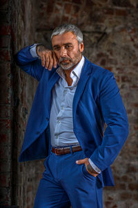 Portrait of young man standing against wall