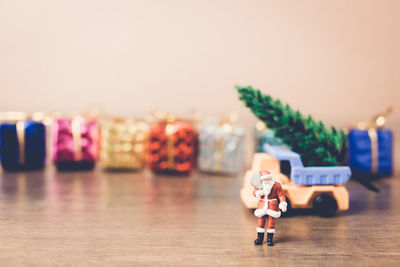 Santa clause figurine with toy truck and christmas presents on table