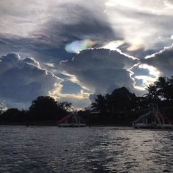 Boats in river against cloudy sky