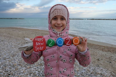 Portrait of girl holding branch with text at beach