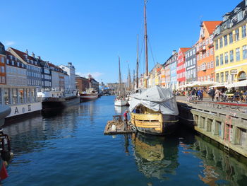 Boats moored at harbor against clear sky