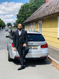 Portrait of young man standing on car