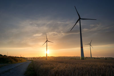 Windmill on farm against sky during sunset