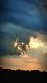 Low angle view of storm clouds over silhouette landscape