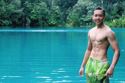 Portrait of smiling young man standing in beautiful lake at labuan cermin biduk biduk