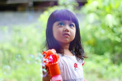 Cute girl holding toy standing outdoors