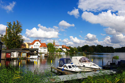 Boats moored in calm lake against houses