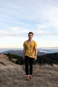 Portrait of young man standing on land against sky