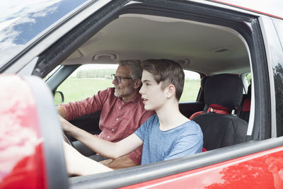 Father teaching son driving a car
