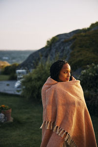 Woman wrapped in blanket looking away while standing on island