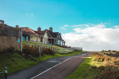 Road amidst buildings against blue sky