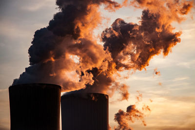 Smoke emitting from factory against sky during sunset