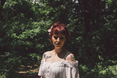 Young woman standing against trees