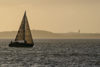 Sailboat sailing on sea against sky during sunset