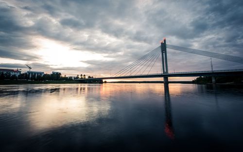 View of suspension bridge over river against cloudy sky