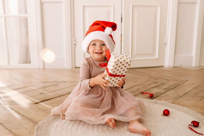 A cheerful emotional little child girl in  santa claus hats is having fun on the christmas holiday