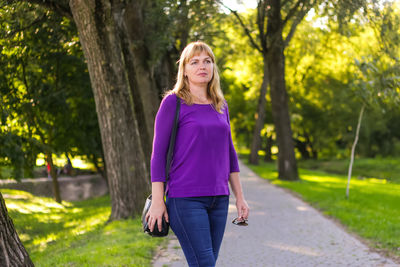Portrait of young woman standing against trees
