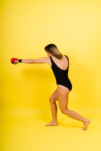 Full length of woman exercising against orange background