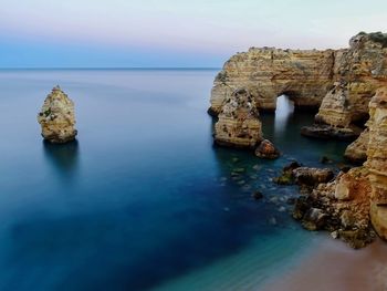 Rock formation in sea against sky