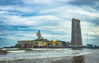 View of building by sea against cloudy sky