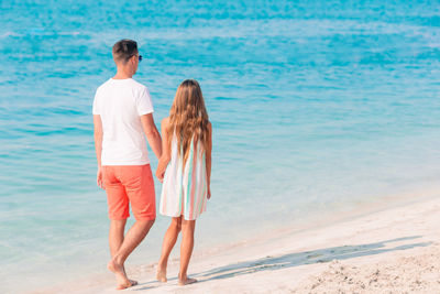 Rear view of friends standing on beach