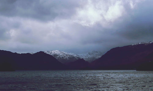 Scenic view of sea by mountains against sky