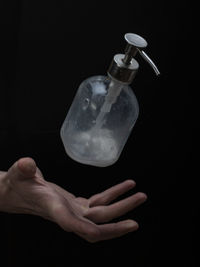 Midsection of man holding glass against black background