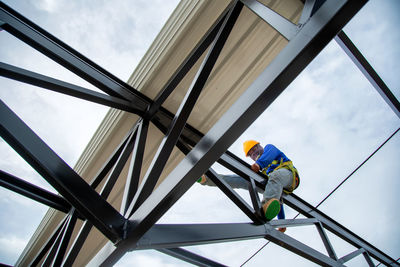 Asian construction workers are installing metal roofing sheets for industrial roof installations.