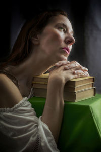 Woman in a white blouse with a carmen neckline with her hands resting on an old book 