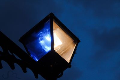 Low angle view of illuminated lamp against blue sky