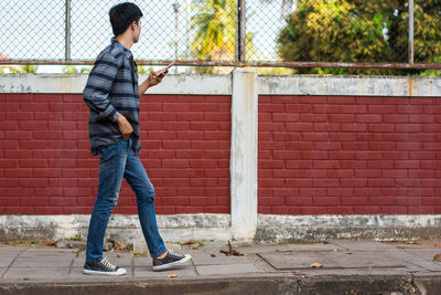 Man using mobile phone while walking on sidewalk