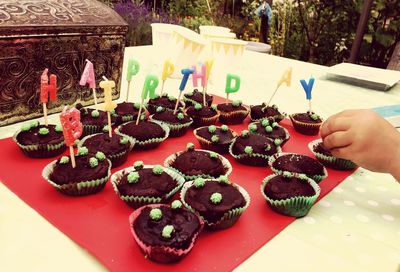 Close-up of hand holding cake served on table