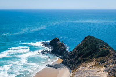 Scenic view of black cliffs against sea against sky