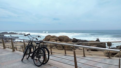 Bicycles on shore by sea against sky