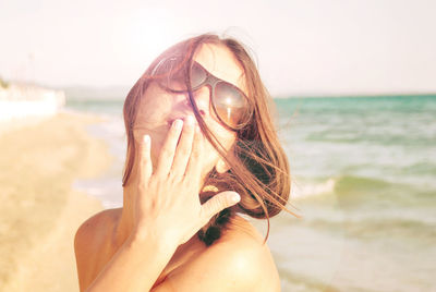 Close-up of young woman with hands on sand at beach