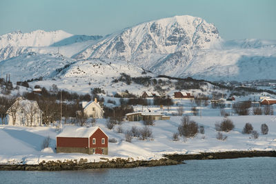 Houses by snowcapped mountains against sky