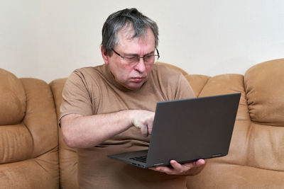 Man using mobile phone while sitting on sofa at home