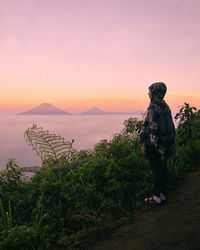 Man standing by plants against sky during sunset