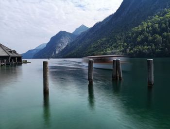 Wooden posts in lake against mountains