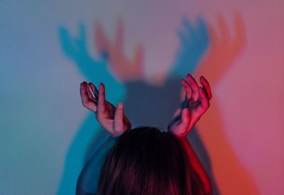 Rear view of woman with hands on head by wall