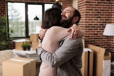 Side view of smiling couple embracing at home
