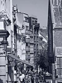 People on street amidst buildings in city against sky