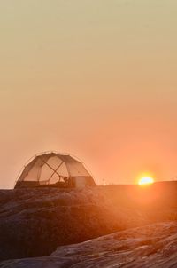 Traditional windmill against sky during sunset
