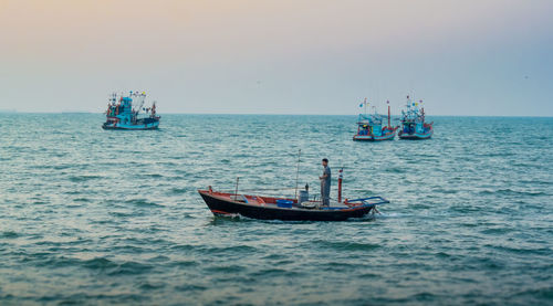 Man standing in boat on sea against sky