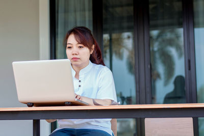 Mid adult woman using mobile phone while sitting on table