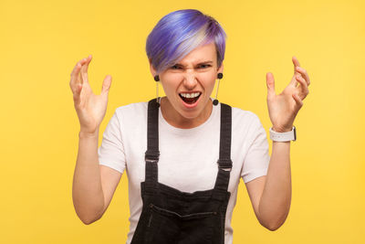 Portrait of young woman standing against yellow background