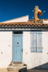 Low angle view of blue door and window shutters of a rural building against clear sky