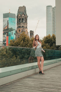 Beautiful young woman standing against buildings in city