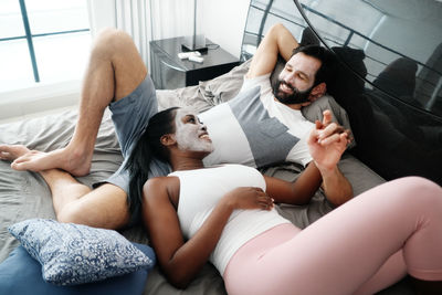 High angle view of friends lying on bed at home